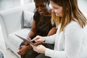 two women on couch looking at ipad
